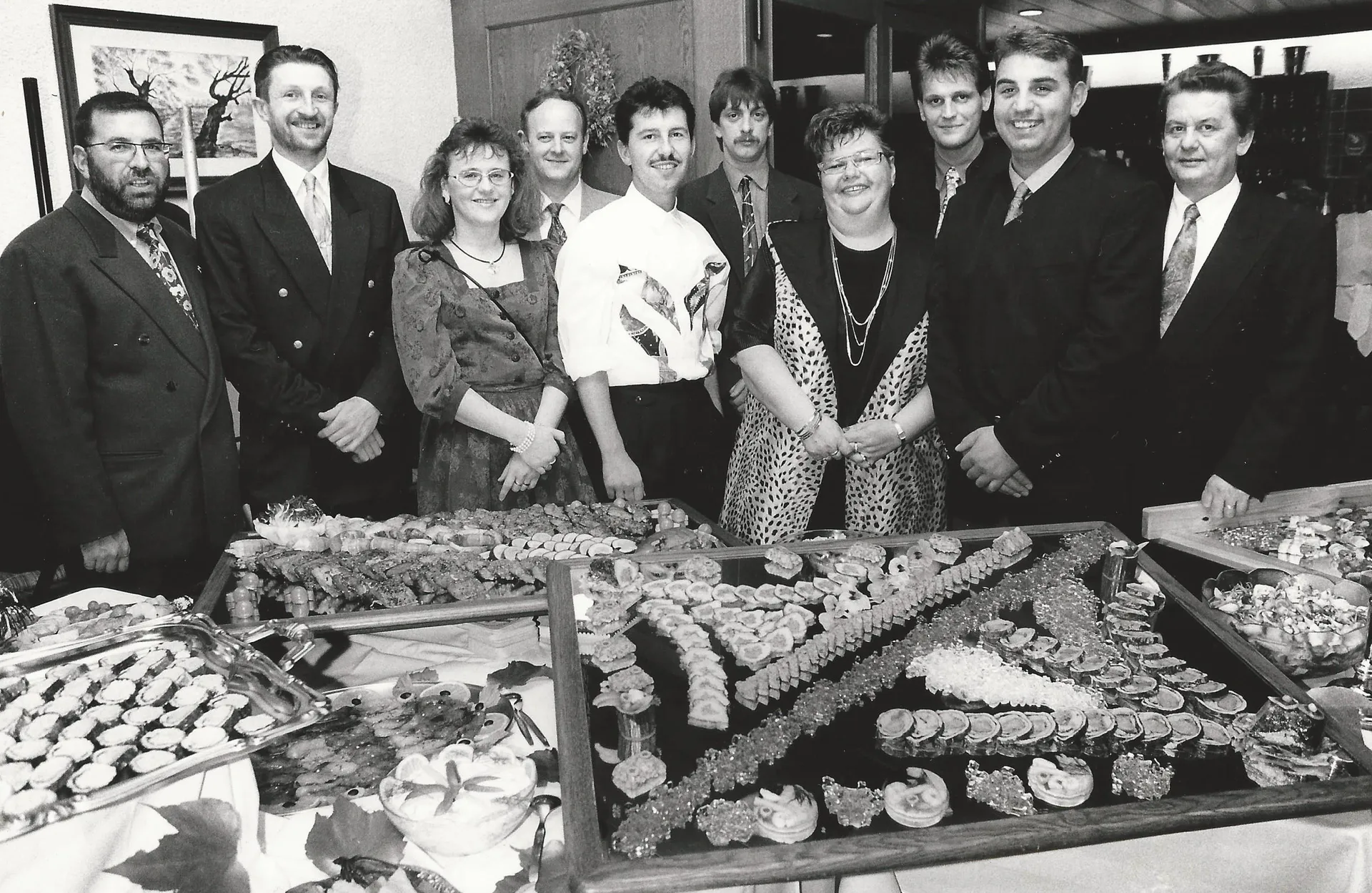 Die Schlemmerwirte gemeinsam hinter einem reich gedeckten Buffet (historische Aufnahme)